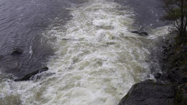 River floodwater rushing out to fjord during heavy rain, Norway
