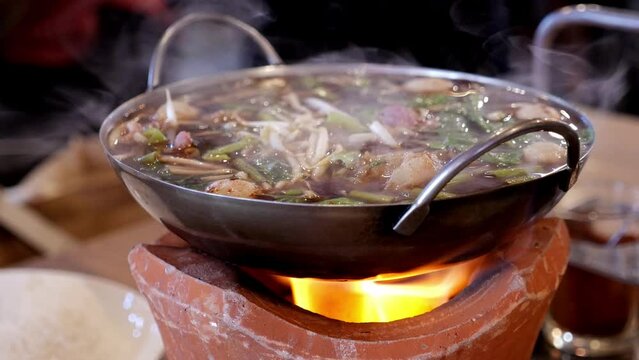 Cooking spicy oxtail noodle soup on a firewood stove