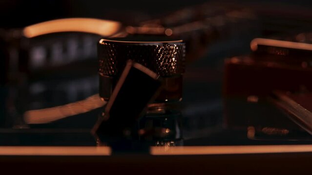 Extreme close up of guitar volume or tone knob or potentiometer. Pickup selector switch on foreground and humbucker pickup on background. Reflections move with camera movement, guitar rotating in shot