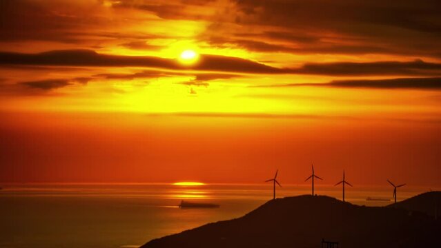 The beauty of nature is depicted in this time-lapse photograph of the sea and wind turbines during sunset in Malaga, Spain, showcasing Galax's elements.