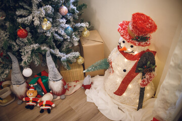 Decorate the christmas tree with small multi-colored balls and snowman, santa claus doll, gift boxs and toy on wooden floor