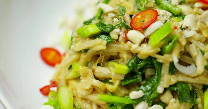 Noodle plate rotating in 4K. Coriander chilli and garlic noodles shallow depth of field image. Healthy vegetarian and plant-based cooking footage.