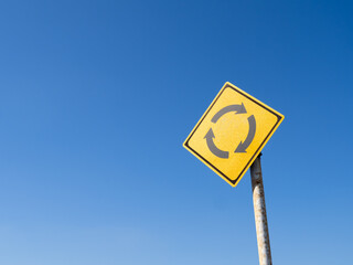 道路標識(警戒標識)「ロータリーあり」と青空。
