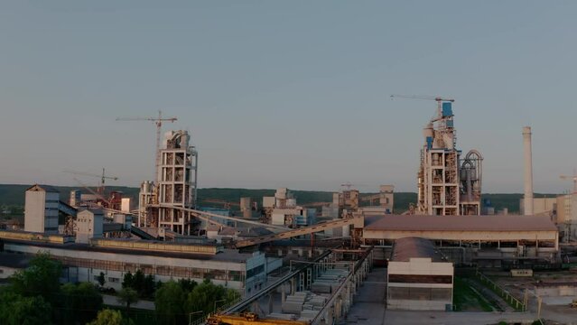 Cement plant with high factory structure at industrial production area at sunset. Aerial drone view 4k futage
