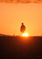 Silhouette of a man on the beach at sunrise.