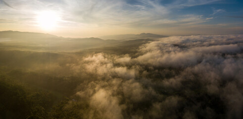 Aerial view of morning sunrise of tropical rainforest at dawn with misty and foggy cloud during summer for outdoor mountain valley landscape