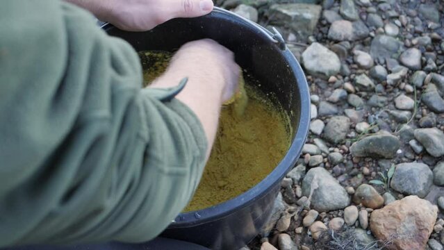 Man mix fishing bream bait in bucket, slow motion.