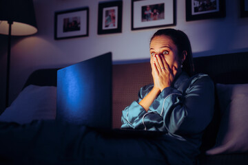 Stressed Woman Watching the News online during Nighttime. Shocked overwhelmed viewer streaming all...