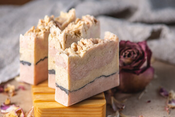 Delicate cute pieces of natural soap on a wooden soap dish on a background of fabric and pink...