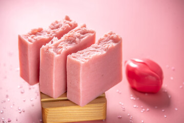 Cute pink pieces of organic eco soap on a soap dish made of natural wood on a pink background. Concept of modern and safe cosmetic products for skin care