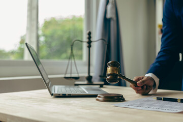 Male lawyer working at table in office focusing on scales of justice, lawyer holding pen and giving legal advice, business dispute service with hammer Close-up pictures