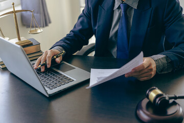 Male lawyer working at table in office focusing on scales of justice, lawyer holding pen and giving legal advice, business dispute service with hammer Close-up pictures - obrazy, fototapety, plakaty