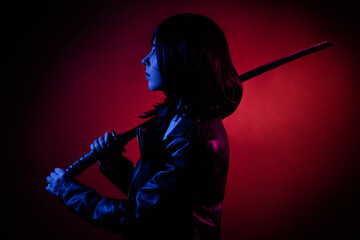 Silhouette in the dark, portrait of a young woman with a bob hairstyle in a black leather jacket...