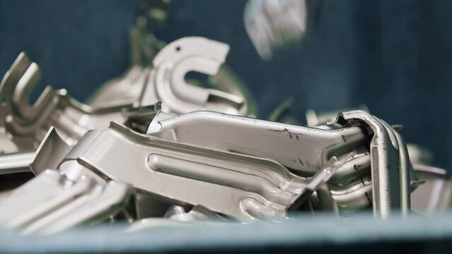 Close up of a pile of car parts falling off the production line after being pressed into shape by a big hydraulic press in the automated production line