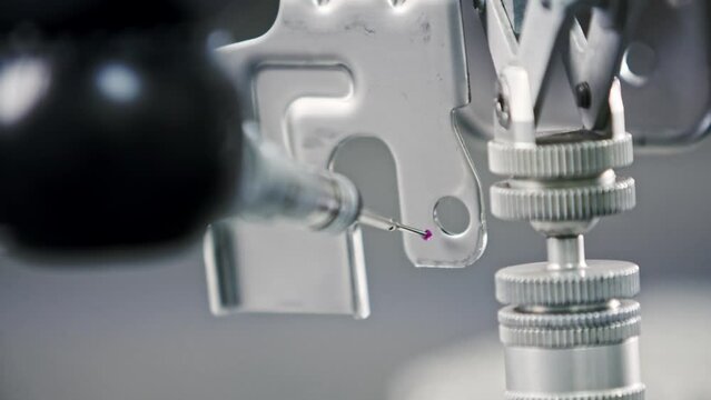 Close up of a measuring needle on a CNC machine that is used for testing deviations in metal products that are created in an automated factory