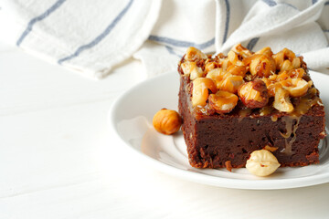 Piece of brownie cake with hazelnuts on white background