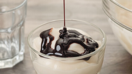 Close-up view of pudding in a glass. Topping vanilla pudding with dark chocolate sauce.