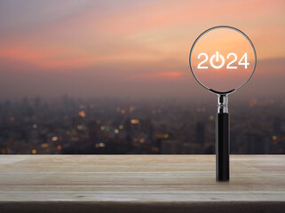 2024 start up flat icon with magnifying glass on wooden table over blur of cityscape on warm light sundown, Business happy new year 2024 cover concept