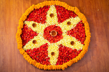 Top view shot Flower decorated diwali festival rangoli with diya lamps on floor at home.