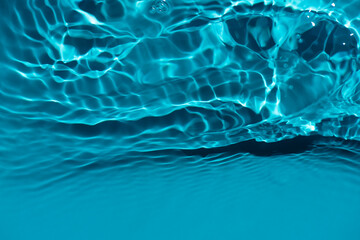 Defocus blurred transparent blue colored clear calm water surface texture with splashes reflection. Trendy abstract nature background. Water waves in sunlight with copy space. Blue watercolor shine.