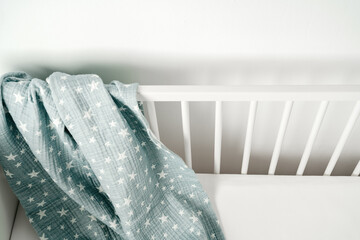 Soft blue muslin blanket hanging on a baby's bed - obrazy, fototapety, plakaty
