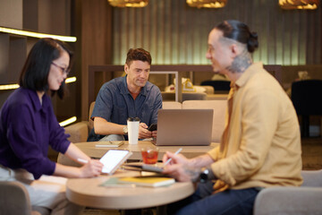 Fototapeta na wymiar Smiling mature businessman working on laptop in coworking space