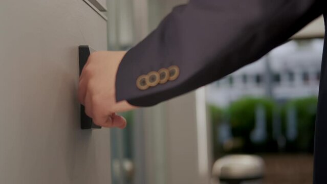 Man in suit opens the door to office building, using a NFC key card,