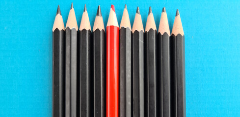 On blue surface, in strict order tips of red pencils were placed among black pen - Powered by Adobe