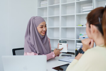 A female Muslim bank employee, making an agreement on a residential loan with a customer.