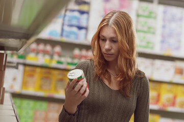 Woman doing grocery shopping and checking information on a product label