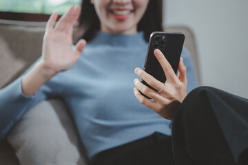 A young woman sits and chats with a friend via video call on a couch at home, Relax in the living room at home on holiday, Live a comfortable life, Sitting on the sofa at the apartment.
