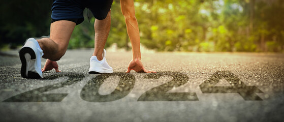 Male runner legs in starting position on road running into new year 2024, beginnings, goals and...