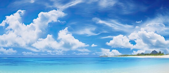 The clear blue sky reflects in the tranquil sea as the white clouds gracefully float above the sandy beach creating a breathtaking landscape that embodies the essence of summer travel and th