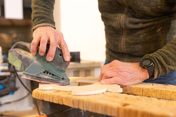 Close-up of a carpenter polishing a piece of wood