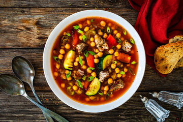Fresh vegetable soup with meat, chickpeas and lentil on wooden table
