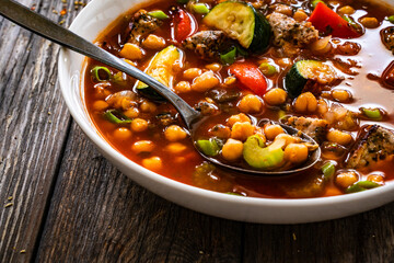 Fresh vegetable soup with meat, chickpeas and lentil on wooden table
 - obrazy, fototapety, plakaty