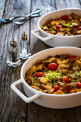 Bread casserole with mozzarella cheese, tomatoes and scrambled eggs on wooden table
