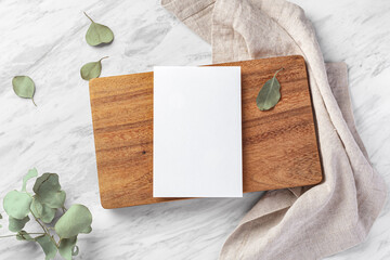 Menu card mockup on wood board with linen napkin on marble table
