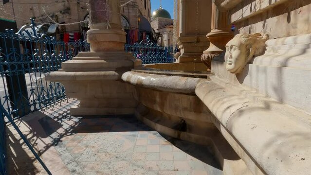 Tilt up of the Muristan fountain running trickle of water, Old City Jerusalem