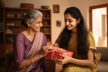 indian ethnic loving mother and daughter exchanging a gift box