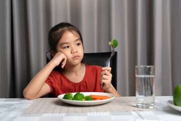 Little cute kid girl refusing to eat healthy vegetables. Children do not like to eat vegetables.