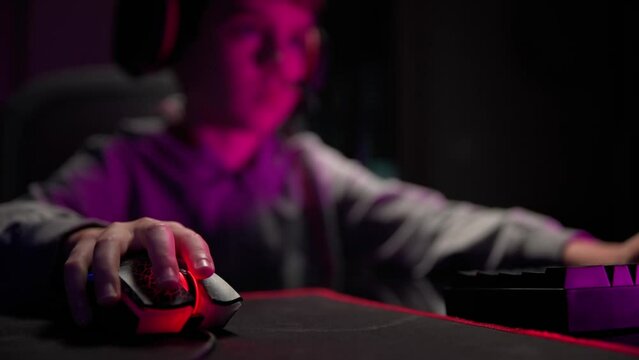 Close up shot of gamer clicking pc mouse button. Teenager boy plays computer video game in dark room, cybersport gaming, children gaming addiction