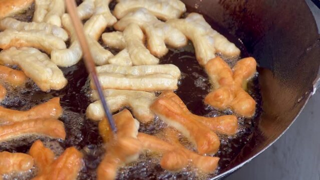 4K deep-fried dough stick or patongko being fried in a pan with boiling oil, Thailand street food breakfast favorite among tourists