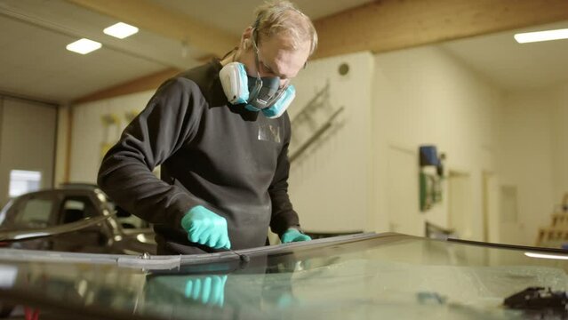 Workshop technician applying primer for adhesive on car windshield
