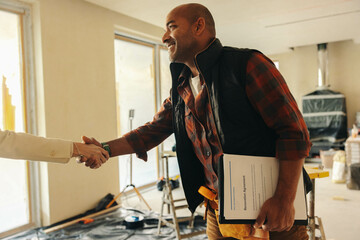 Professional contractor shakes hands with happy homeowner for interior renovation project - obrazy, fototapety, plakaty