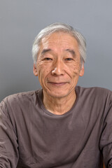 白髪混じりの60代の男性が、作り笑いで営業トークをしている