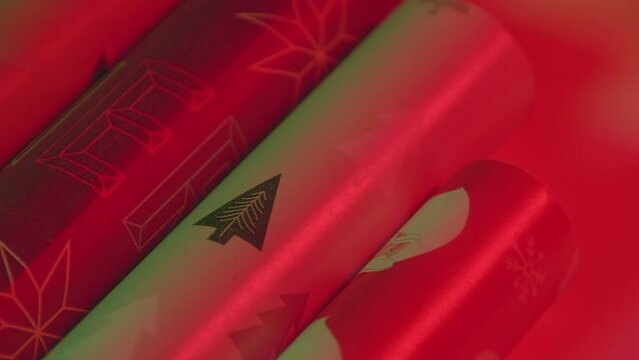 Slow motion close-up pan left to right Christmas tree logo on wrapping paper roll, vibrant red green two-light