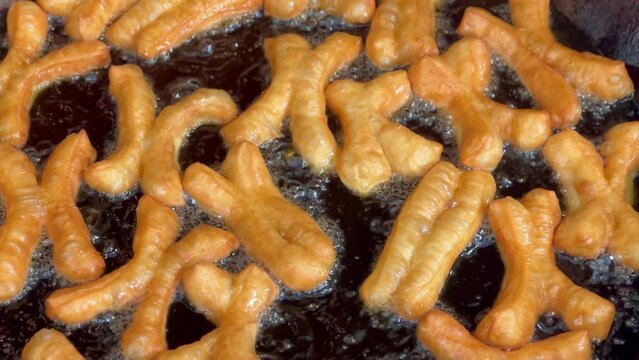 4K deep-fried dough stick or patongko being fried in a pan with boiling oil, Thailand street food breakfast favorite among tourists