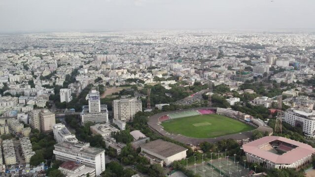 A cinematic aerial video shows Egale flying towards a cricket stadium in Hyderabad, close to the Birla Science Museum and Birla Planetarium. huge city antenna tower. Hyderabad's metro rail networks