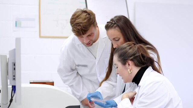 Three young scientist coworkers analysing samples in a laboratory. Chemist group working together